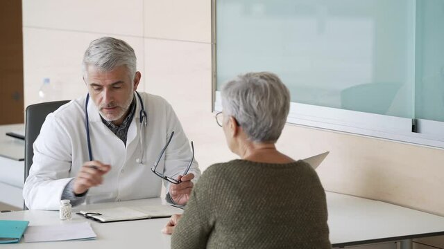 Mature doctor in office listening to patient