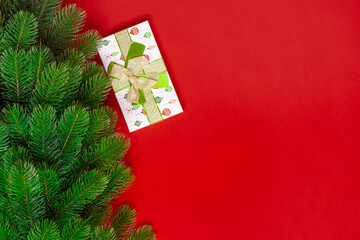 mock up of a Christmas tree and a green gift box on a red background with space for text.