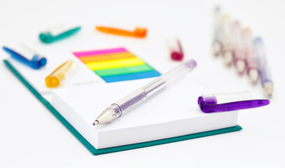 Various colored pencils, paper, notes on white background.