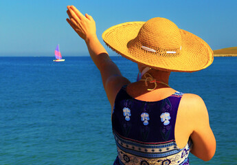 Unknown woman observing sea under clean sky.