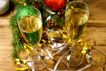 Two glasses of champagne and festive Christmas decorations on wooden table. Christmas and New Year celebration