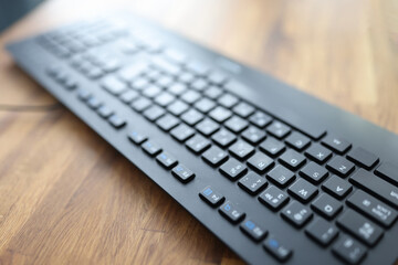 Black keyboard lying on wooden table in office closeup. Repair and sale of computer equipment concept