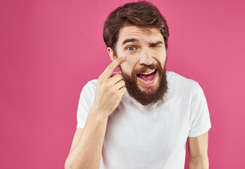 Happy man holds his hands near his face and laughs on a pink background