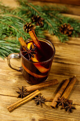 Christmas mulled wine with spices and fir tree branches and cones on wooden table