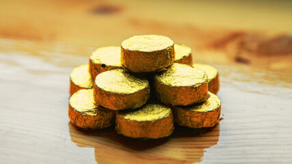 Chinese tea ripe puer in the form of pills wrapped in gold foil, arranged in the form of a pyramid, standing on top of each other, close-up image. 