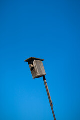 Handmade wooden birdhouse on the background of a bright blue sky. Feeding and caring for birds in winter.