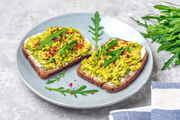 Set sandwiches for breakfast - slice of whole grain dark bread, cream cheese, guakomole, garnished with arugula, paprika on concrete table Top view Flat lay Healthy food concept Homemade