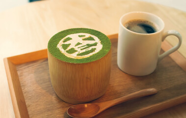 Tray with a Matcha Parfait in a wooden bowl and a cup of coffee in the background
