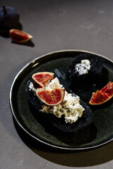 Sandwich with Ricotta, blue cheese and fresh Figs on plate on dark concrete background. Simple healthy breakfast. Smørrebrød. Very bkack bread