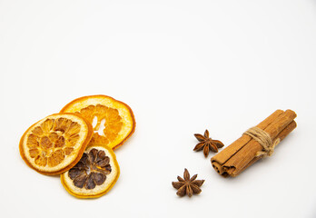 A few slices of dried orange, cinnamon sticks and star anise on a white background.