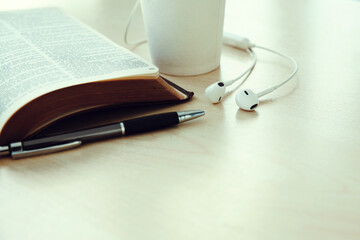 Open book with cup of coffee,pen,Earphone on wooden desk