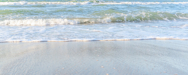 Fototapeta na wymiar the waves of the sea on the sandy beach on a sunny day