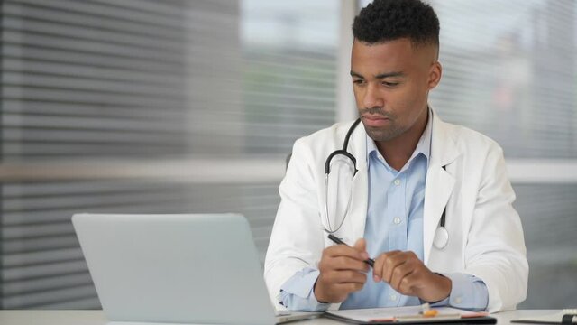 Medical intern working on laptop at hospital office