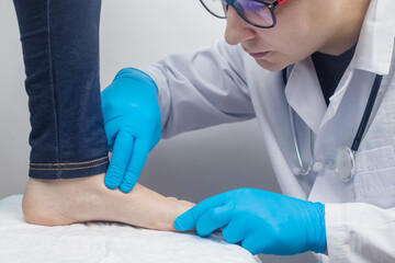 An orthopedic surgeon examines a woman's leg. Foot pain, tendon sprains, inflammation, flat feet,...