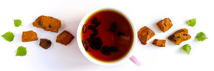Cup of tea of birch chaga mushroom and crushed chaga fungus pieces for tea brewing isolated on a white. bannerbackground