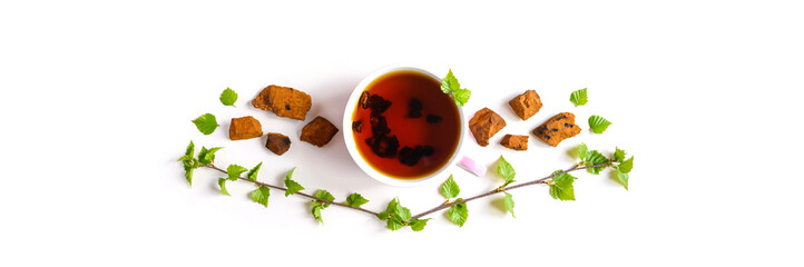 Cup of tea of birch chaga mushroom and crushed chaga fungus pieces for tea brewing isolated on a white. bannerbackground