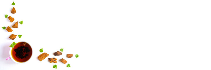 Cup of tea of birch chaga mushroom and crushed chaga fungus pieces for tea brewing isolated on a white background. banner. space for text