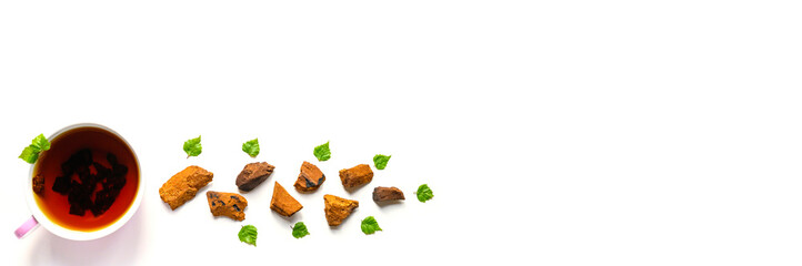 Cup of tea of birch chaga mushroom and crushed chaga fungus pieces for tea brewing isolated on a white background. banner. space for text