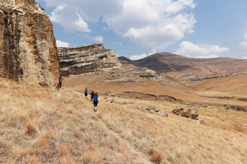 Hikers walking in the Golden Gate National Park along a path in single file towards the sandstone...