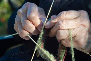 Close-up of an old woman's hand using needles to knit traditional Serbian woolen socks