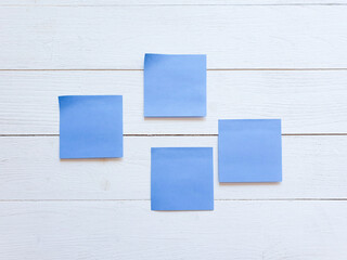 Four blue paper stickers on white wooden board wall.