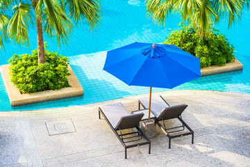 Beautiful empty chair with umbrella around outdoor swimming pool