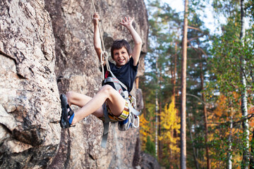 Naklejka na ściany i meble cute teen kid climbing on rock with insurance, lifestyle sport people concept