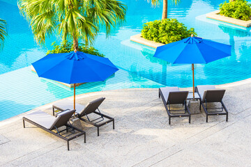 Beautiful empty chair with umbrella around outdoor swimming pool