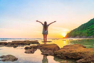 Obraz premium Portrait asian woman stand on the rock at sunset around beach sea ocean
