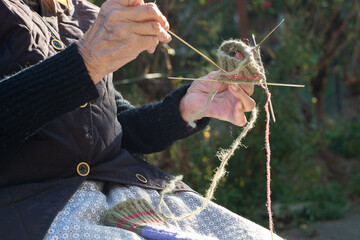 Close-up of an old woman's hand using needles to knit traditional Serbian woolen socks