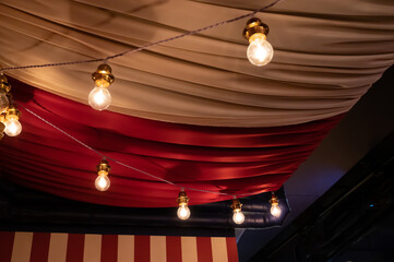 Ceiling decorated with heavy fabrics and light bulbs to show a circus feeling