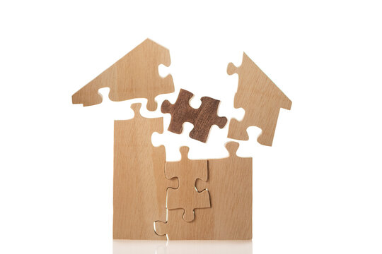 House built out of puzzle pieces on wooden background