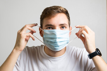 Boy putting the rubber of the mask on his ear. Concept of health, virus, pandemic