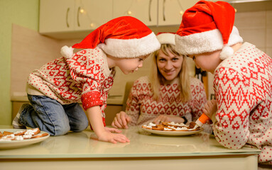 Adorable boys decorating gingerbread cookies with fun. Xmas holiday