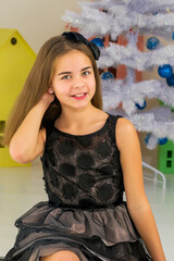 Girl in Stylish Dress Sitting on the Floor in Front of Christmas Tree