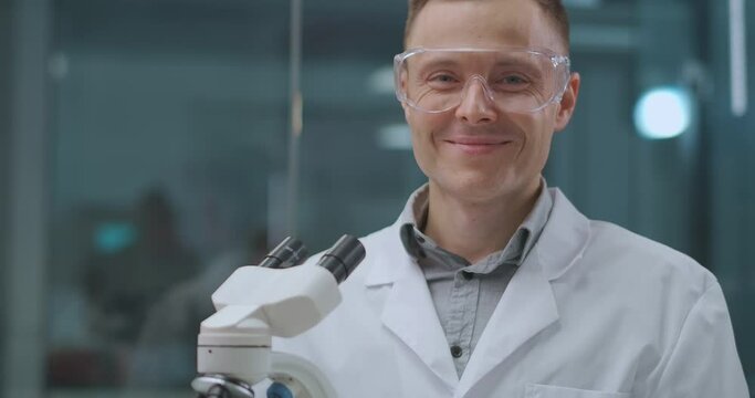 smiling male lab assistant in laboratory, looking at camera, scientist and forensic expert
