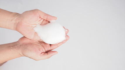 Hands washing gesture with foaming hand soap on white background.