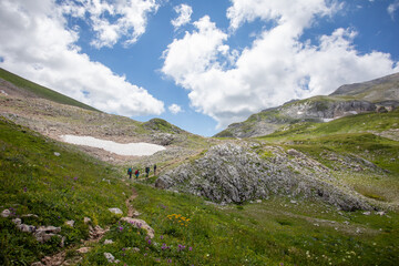 Fototapeta na wymiar Tourists with backpacks walk the trail along the mountain route