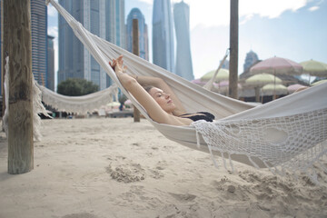 young beautiful woman lying on a hammock at the beach in dubai