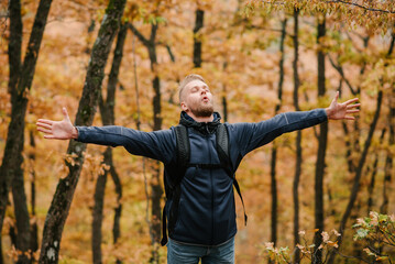 A man traveler in the autumn forest raised his hands.