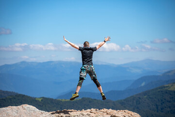 Young man jumping for joy on the top of the mountain