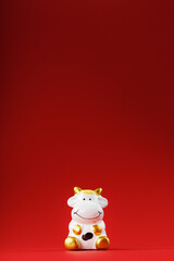 Christmas toy of a cow made of ceramic on a red background. 2021 year of the Bull, cow. New year's symbol