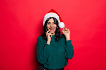 Young woman wearing santa hat have fun isolated on red background