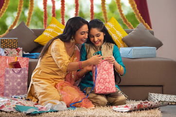 Mother and daughter packing gifts together	