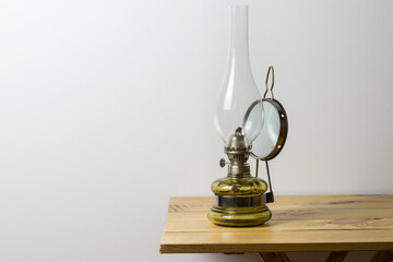 Old kerosene lamp on a wooden table, white wall