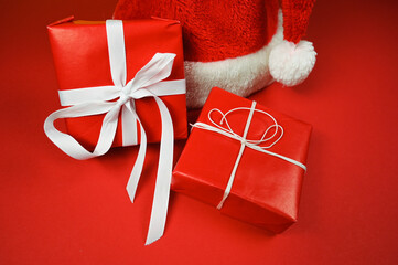 Red Christmas background with santa hat and gift boxes.