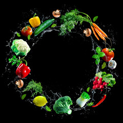 Assortment of fresh vegetables and water splashes on black background