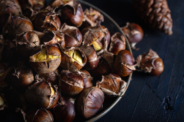 Roasted chestnuts in ceramic dish on dark background. Winter background.