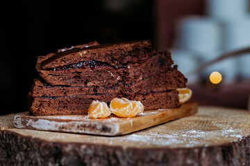 piece of chocolate cake on a wooden bord sprinkled with sugar powder and mandarins