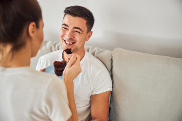 Smiley brunette man being fed with chocolate cake